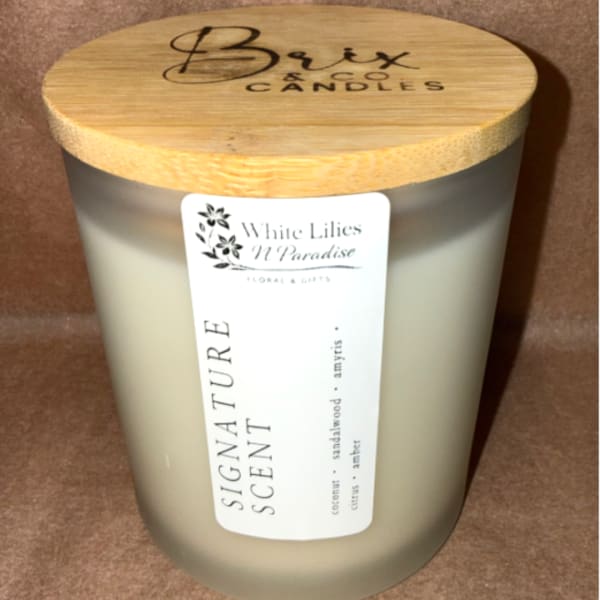 Frosted glass candle jar with a bamboo lid and label