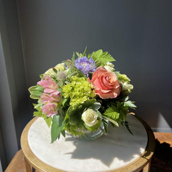 Mixed bouquet of roses, hydrangea, and pink blooms in a glass vase