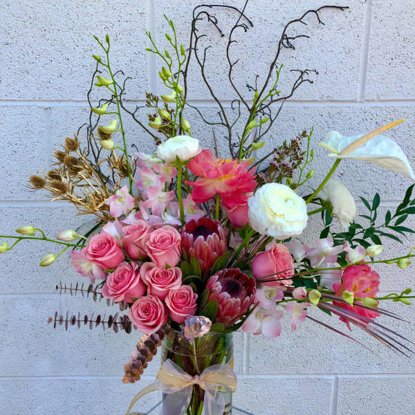Pink roses and white calla lilies in a glass vase with a ribbon