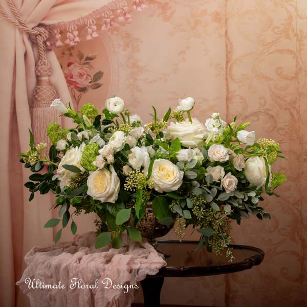 White and blush rose arrangement in a decorative urn