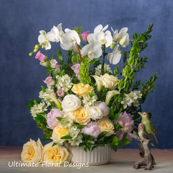 Mixed floral arrangement in a white vase with orchids and roses