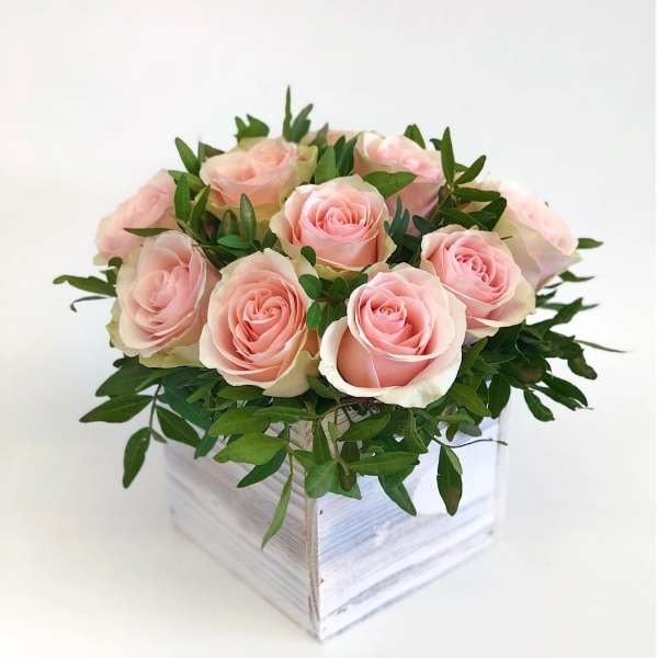 Pink roses arranged in a white wooden box