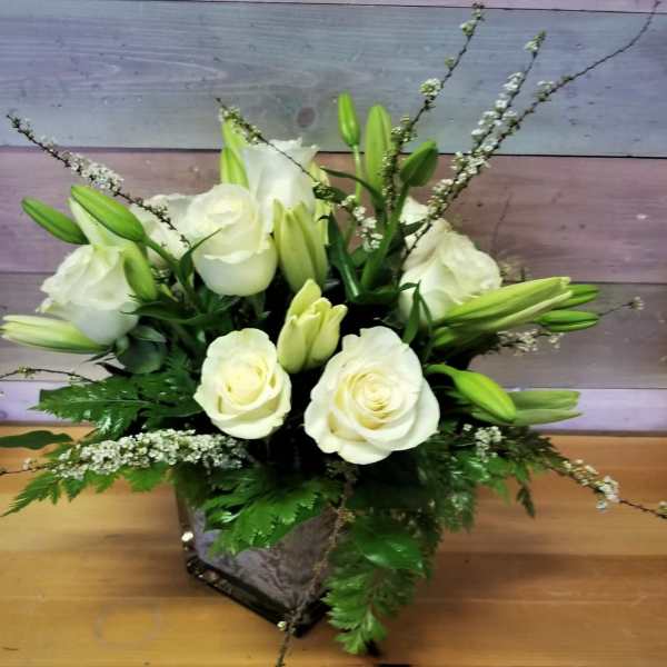 White roses and lilies arranged in a square vase