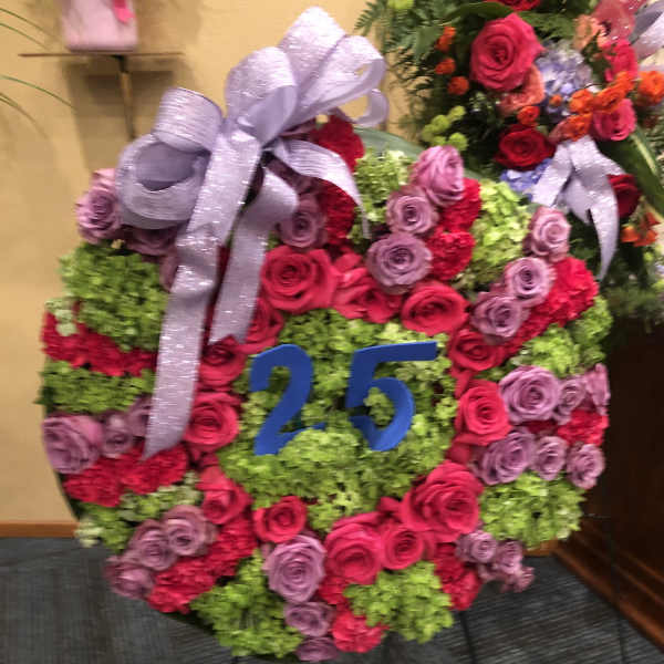 Round floral wreath with pink and lavender roses and a silver bow