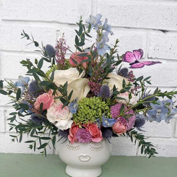 Mixed bouquet in a white face vase with pink, white, and blue flowers