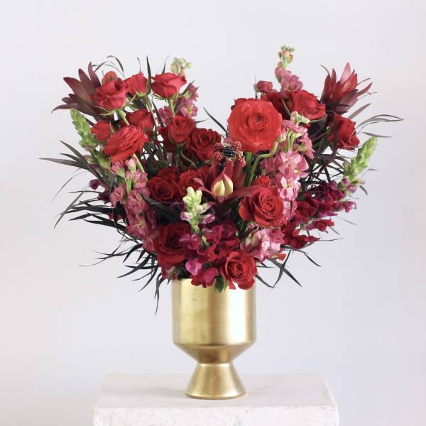 Red and pink floral arrangement in a gold vase