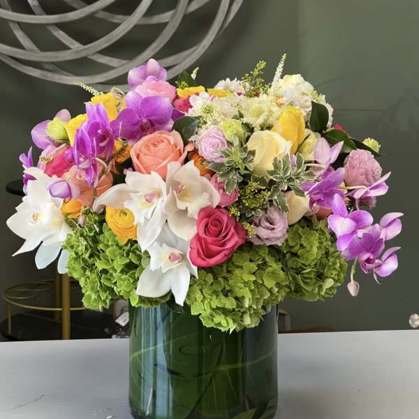 Colorful bouquet of orchids, roses, and hydrangeas in a glass vase