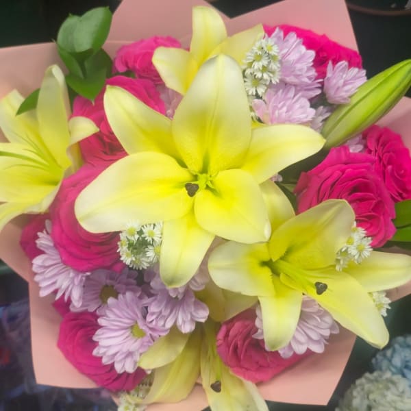 Bouquet of yellow lilies, pink roses, and pale purple daisies