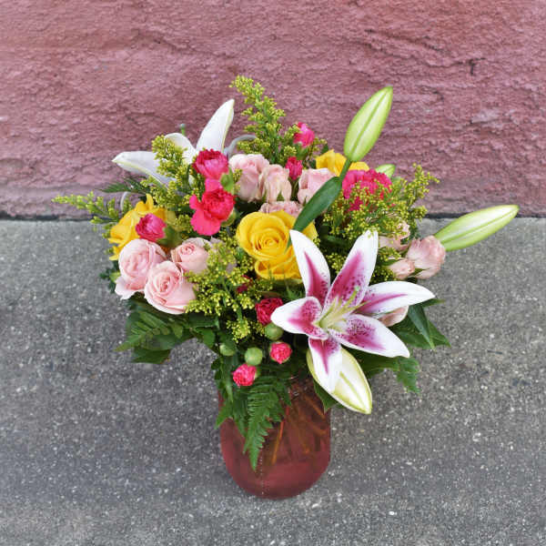 Bouquet of pink and yellow roses with lilies in a glass vase