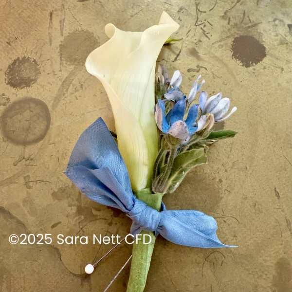 White calla lily boutonniere with blue flowers and a blue ribbon