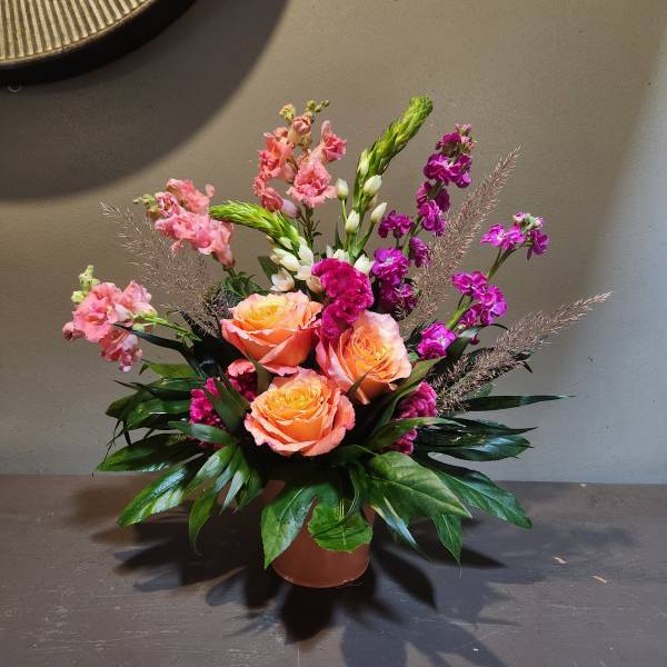 Pink and orange floral arrangement in a round vase