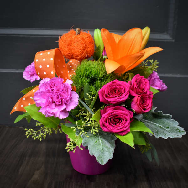 Bright mixed bouquet in a magenta pot with orange lilies and pink roses