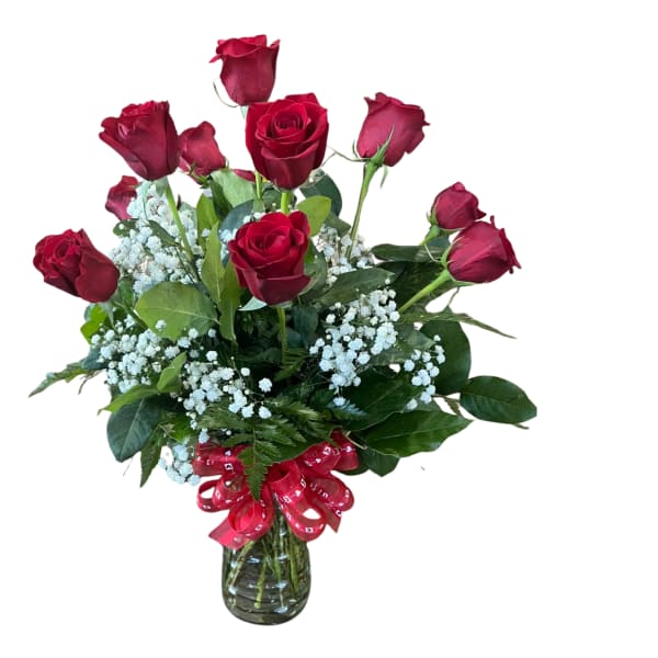 Arrangement of red roses with white filler flowers in a clear glass vase with a red bow