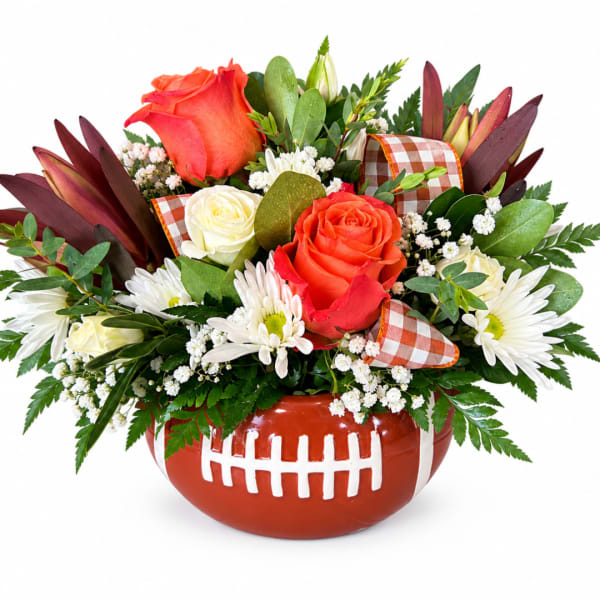 Football-shaped vase with roses and white daisies