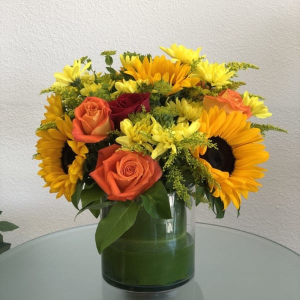 Bouquet of orange roses and yellow sunflowers in a glass vase