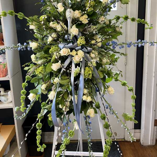 Large standing floral spray with white roses and blue accents on an easel