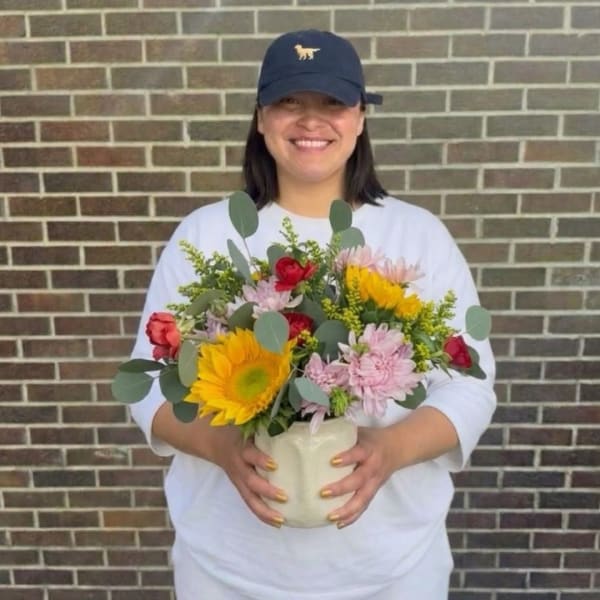 Woman holding a mixed bouquet in a white vase
