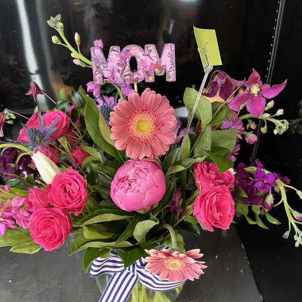Pink floral bouquet in a glass vase with a MOM pick and striped ribbon