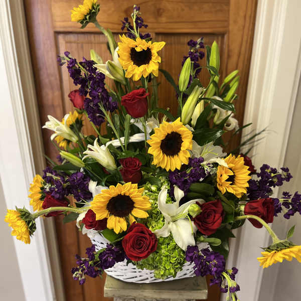 Basket arrangement of sunflowers, red roses, white lilies, and purple flowers