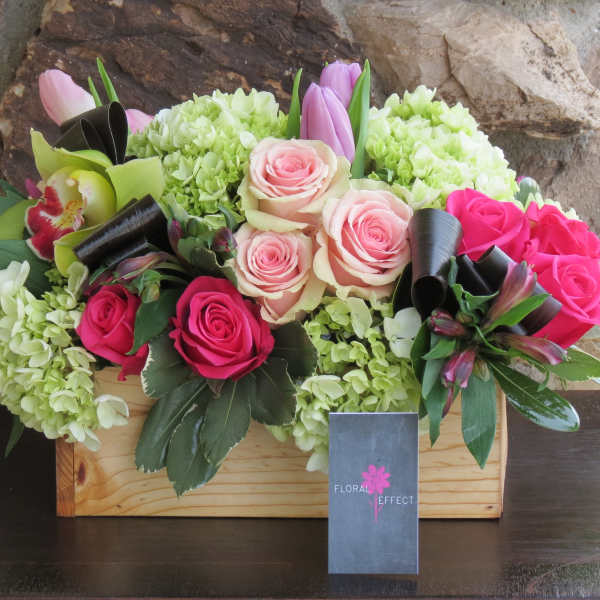 Mixed pink and cream roses in a wooden box with green hydrangeas.