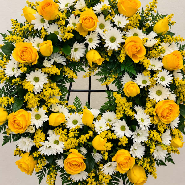 Yellow roses and white daisies arranged in a wreath on a stand