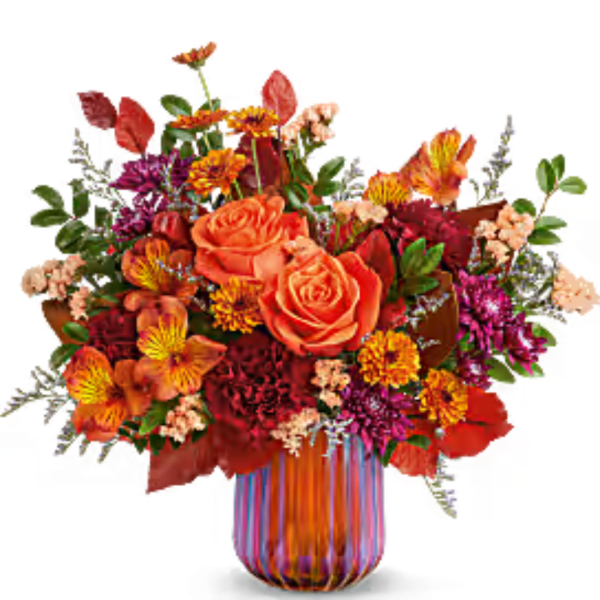 Orange roses and mixed fall flowers in a striped glass vase