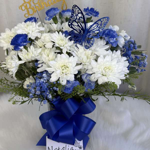 Blue and white flower arrangement with a butterfly topper and ribbon
