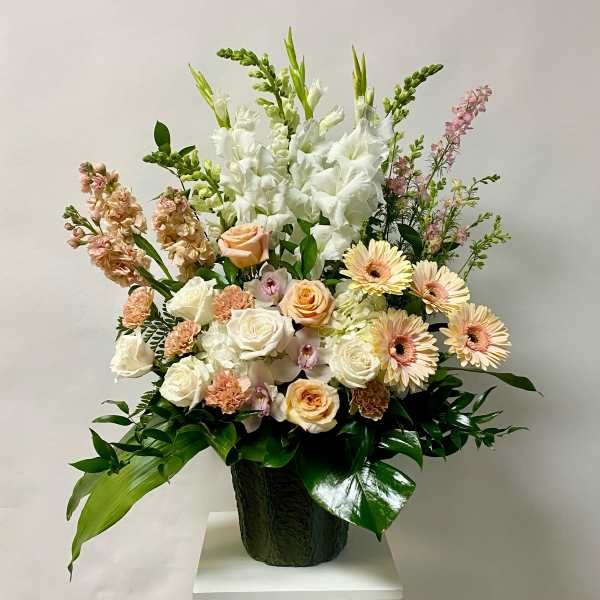 Mixed bouquet with white and peach flowers in a dark vase