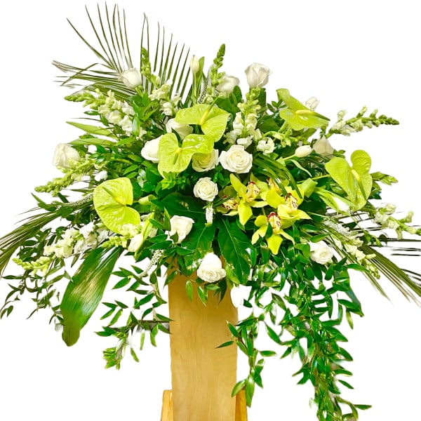 Large white and green floral arrangement in a tall wooden stand