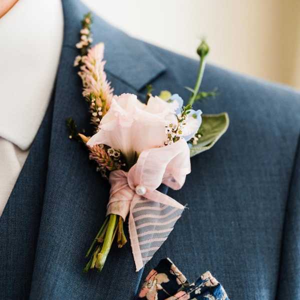 Pink boutonniere pinned to a blue suit jacket