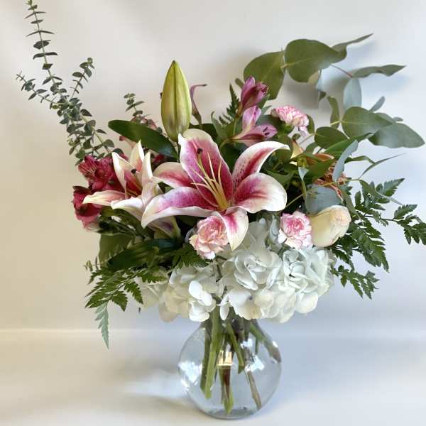 Pink lilies and white hydrangeas in a clear glass vase