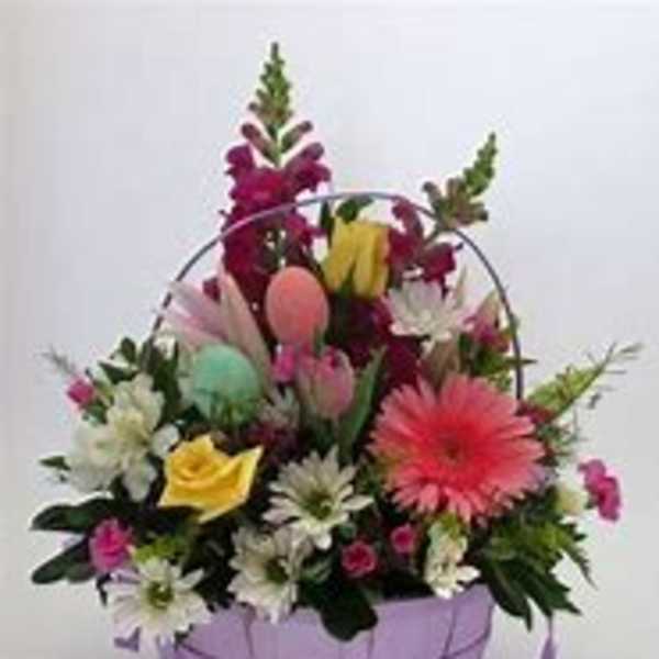 Mixed flower basket with pastel eggs in a lavender container