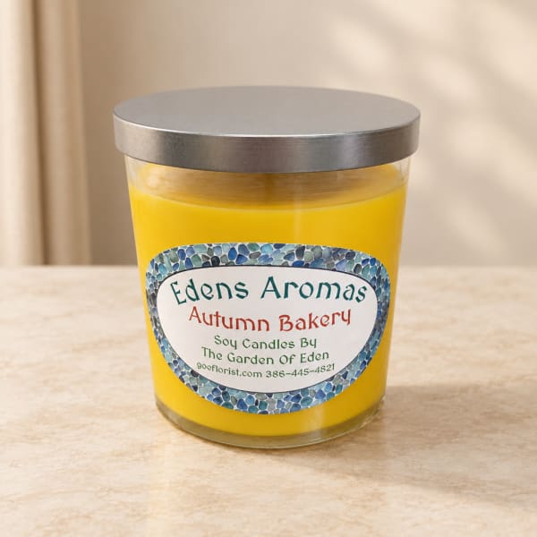 Yellow candle in a glass jar with a silver lid and printed label