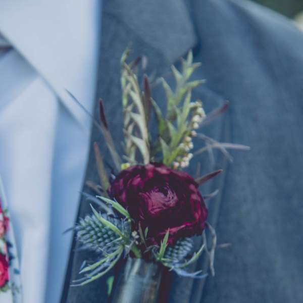 Dark red boutonniere pinned to a suit jacket