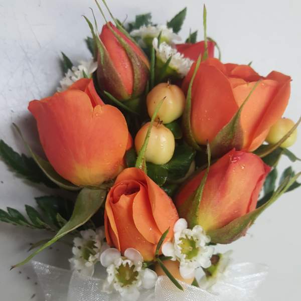 Small bouquet of orange roses with white filler flowers and a white ribbon