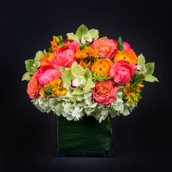 Bright mixed flower arrangement in a square glass vase