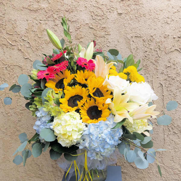 Mixed bouquet with sunflowers, lilies, roses, and hydrangeas in a glass vase