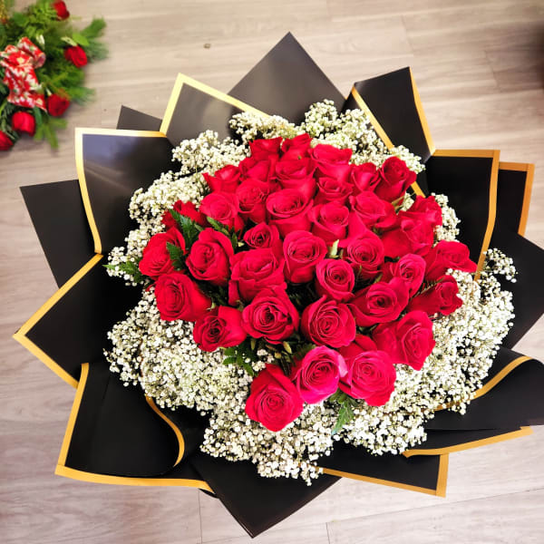 Large bouquet of red roses with white baby's breath in black and gold wrap