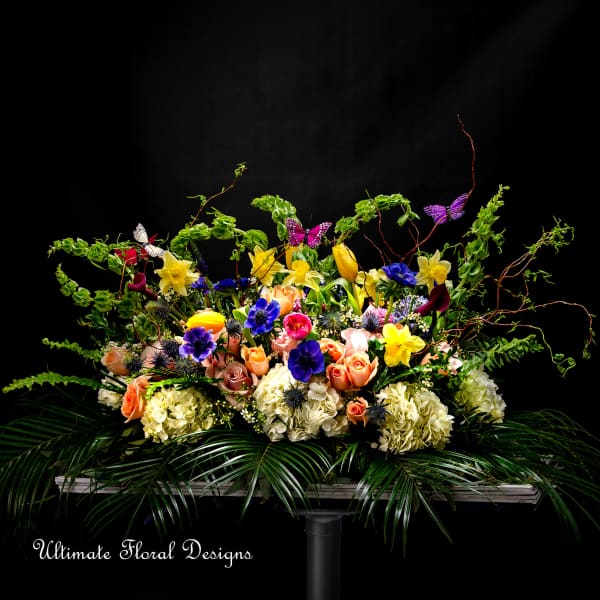 Large floral arrangement with roses, daffodils, hydrangeas, and butterflies