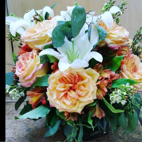 Bouquet of peach roses and white lilies with greenery