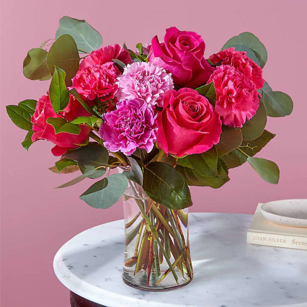 Pink roses and carnations in a clear glass vase