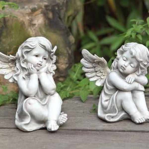 Two small angel figurines sitting on a wooden surface