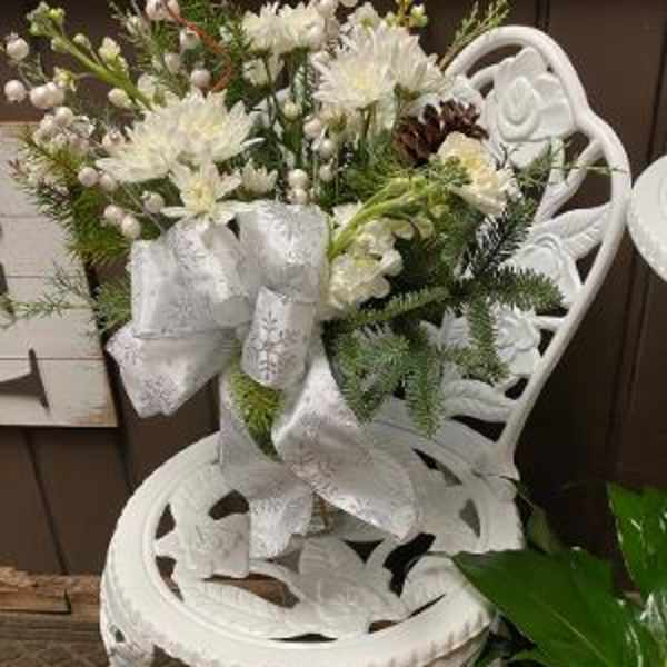 White floral arrangement with ribbon on an ornate white chair
