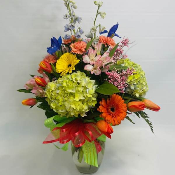 Colorful mixed flower bouquet in a glass vase with ribbon