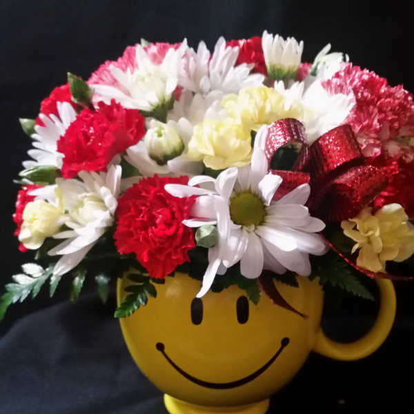 Bouquet of red and white flowers in a yellow smiley-face mug