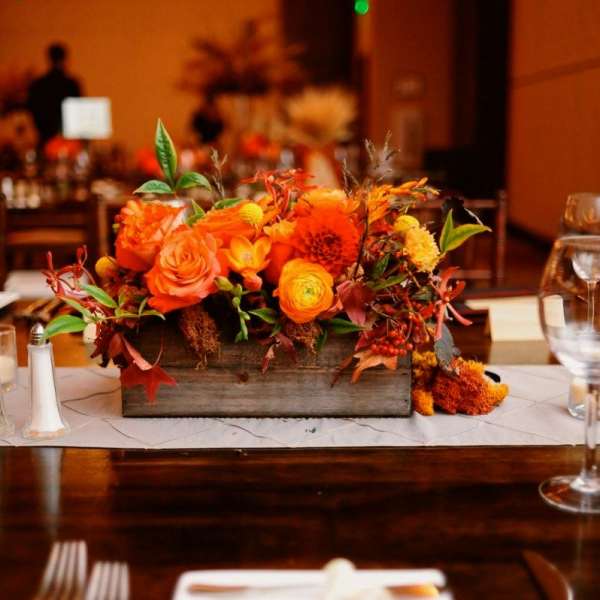 Orange floral centerpiece in a wooden box on a banquet table
