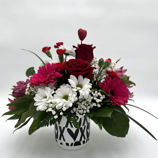 Red roses and pink daisies in a heart-patterned vase