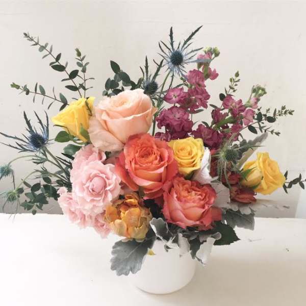 Mixed roses and thistle in a white vase