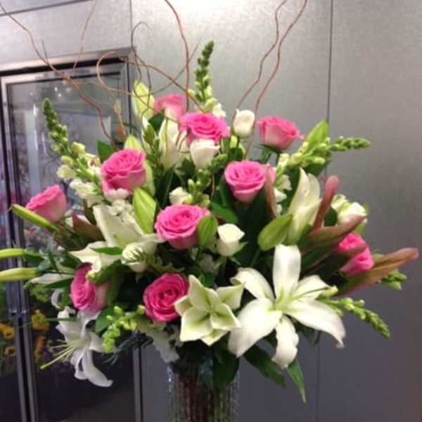 Pink roses and white lilies arranged in a tall glass vase