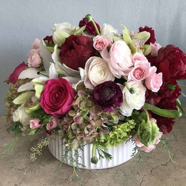 Mixed pink, white, and burgundy flowers in a white bowl vase